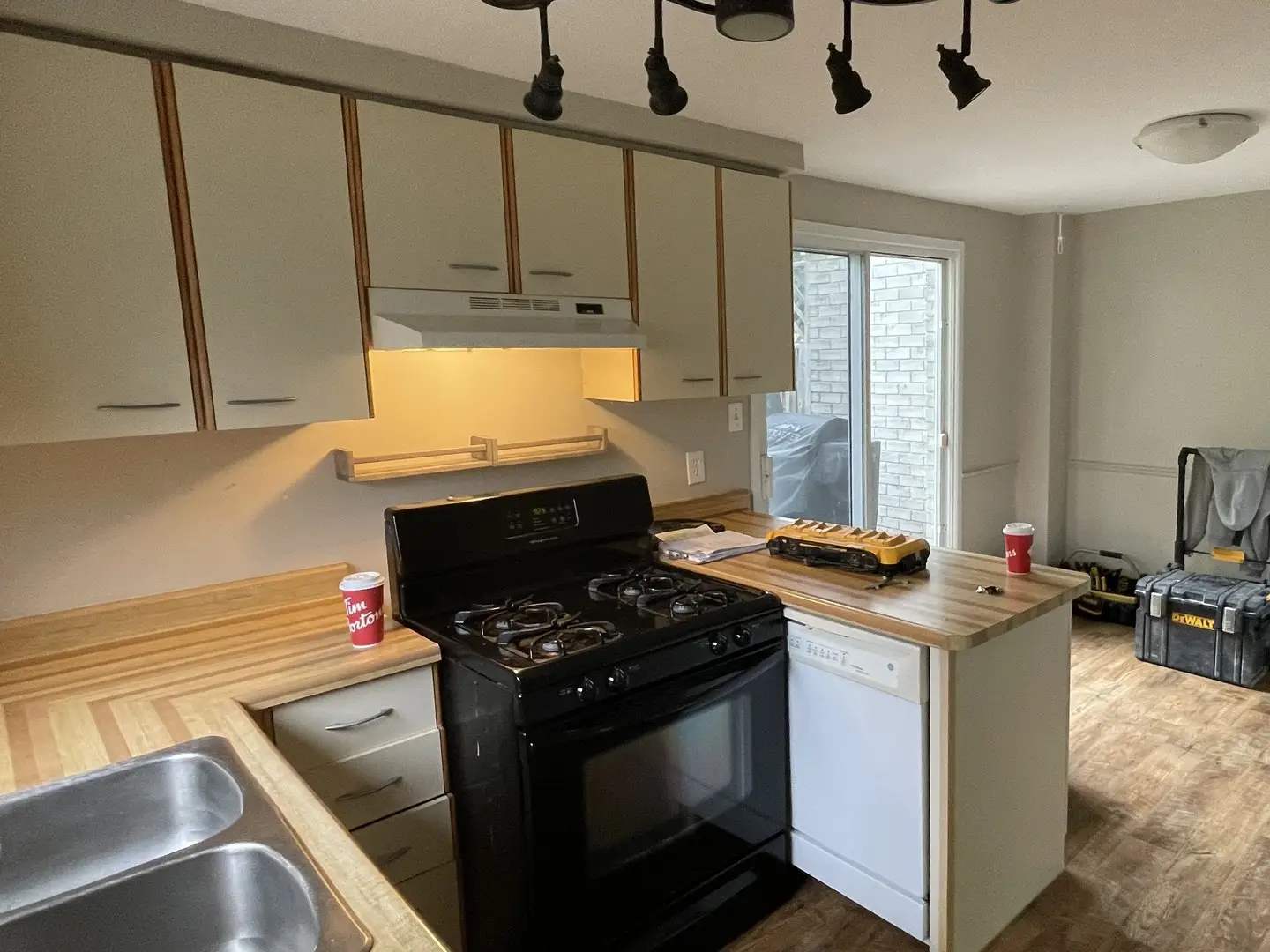 Dated kitchen before renovation — laminate cabinets, wood-edged counters and an old range hood